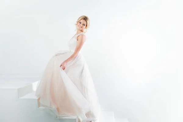 Porträtt av en vacker flicka i en bröllopsklänning. Dansande bruden, vit bakgrund. — Stockfoto