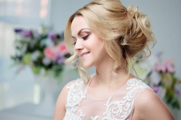 Portret van een mooi meisje in een trouwjurk. Bruid in een luxe jurk op een witte achtergrond, mooi kapsel — Stockfoto