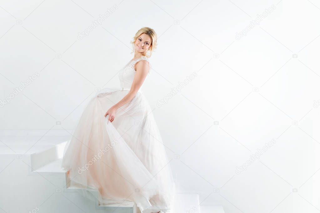 Portrait of a beautiful girl in a wedding dress. Dancing Bride, white background.