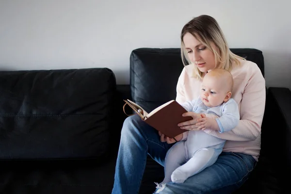 Joven madre y su hijo leyendo un libro, el concepto de desarrollo temprano, interior —  Fotos de Stock