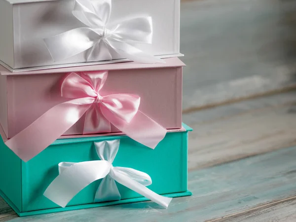 Tre confezioni regalo, bianca, rosa e turchese. Sfondo in legno . — Foto Stock