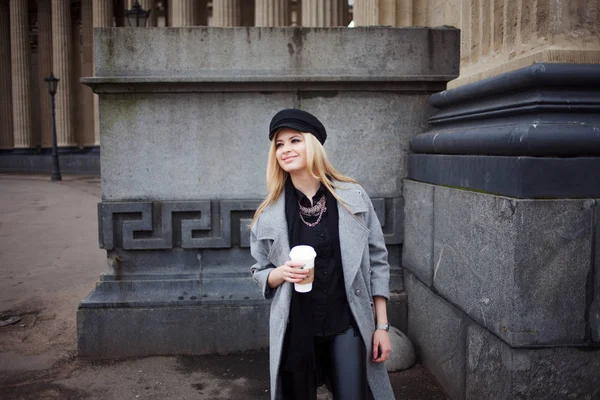 Fille blonde à la mode marchant avec du café à emporter, femme dans un chapeau élégant et un manteau gris — Photo