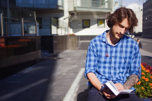 Парень в синей рубашке читает книгу. Портрет молодого красивого стильного мужчины на улице . — стоковое фото