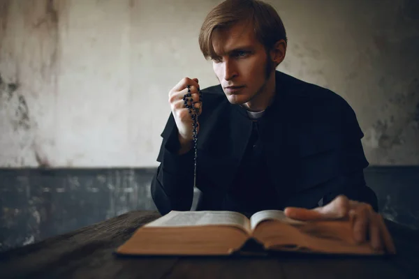 Portrait of handsome young catholic priest praying to God. Dark style, concept doubt — Stock Photo, Image