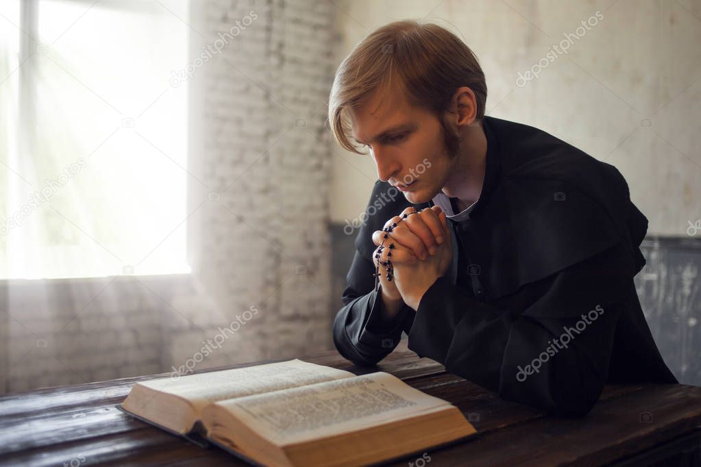 Portrait of handsome young catholic priest praying to God.