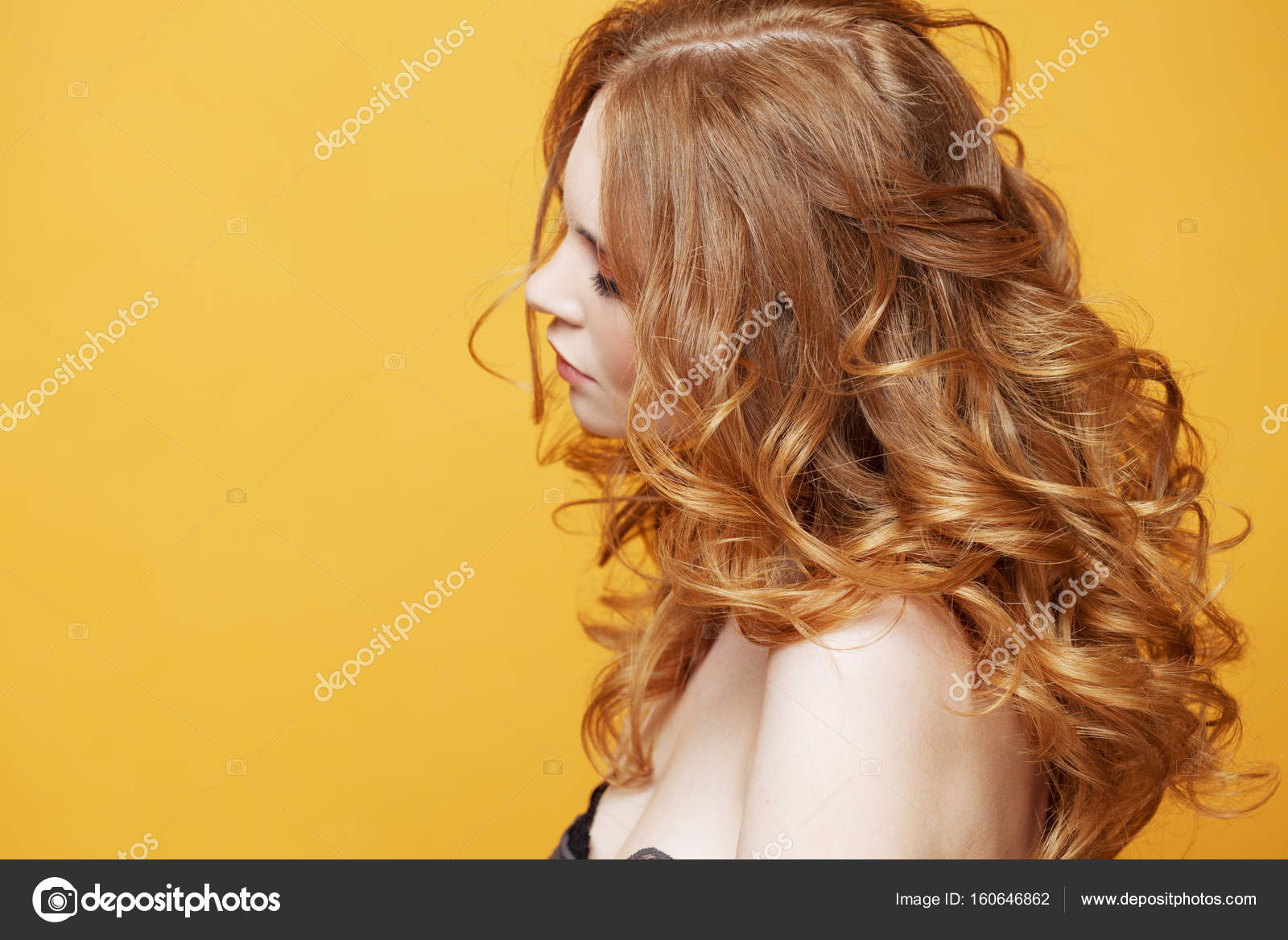 Beautiful redheaded girl with luxurious curly hair. Portrait in profile.  Free space left. Studio portrait on yellow background. Stock Photo by  ©KrisCole 160646862