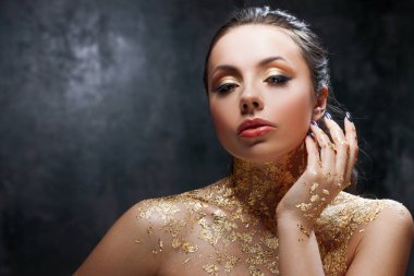Güzel esmer kız altın folyo boyun ile yaratıcı görüntü ile. Stüdyo portre koyu arka plan arka plan üzerinde.