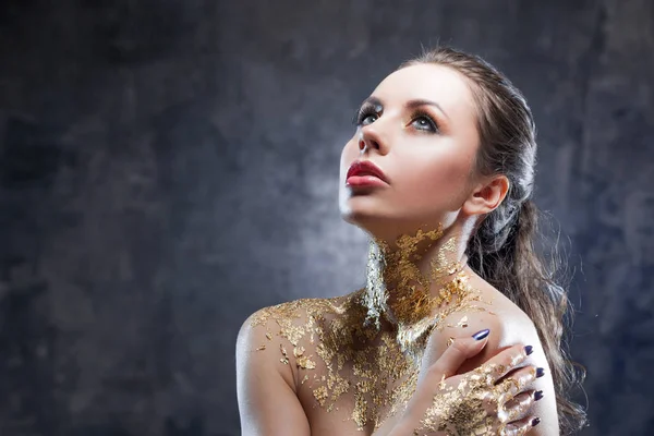 Güzel esmer kız altın folyo boyun ile yaratıcı görüntü ile. Stüdyo portre koyu arka plan arka plan üzerinde.