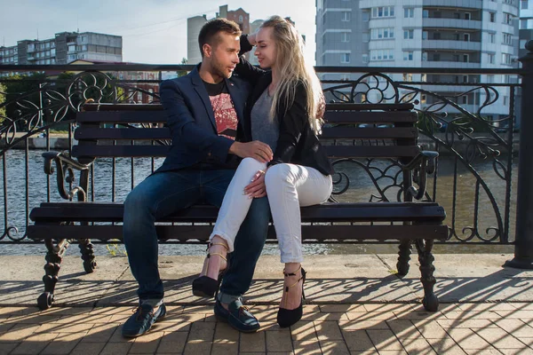 Adultos jóvenes hombre y mujer en un banco de la ciudad. Fecha romántica —  Fotos de Stock