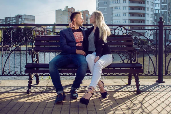 Adultos jóvenes hombre y mujer en un banco de la ciudad. Fecha romántica —  Fotos de Stock