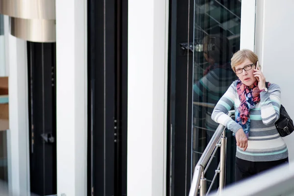 Elegant mogen kvinna använder smartphone, telefon talk, porträtt på köpcentret — Stockfoto