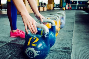 Kettlebell Kulübü. Kız ağırlık çalışmasına hazırlanıyor, uzun döngüye giriyor.