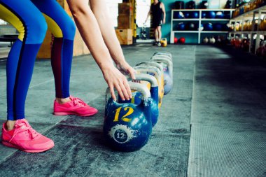 Kettlebell Kulübü. Kız ağırlık çalışmasına hazırlanıyor, uzun döngüye giriyor.