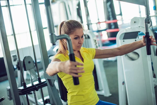 Jonge vrouw atleet zwaait de armen en de rug, het gym — Stockfoto