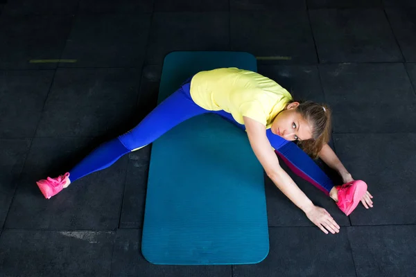 Ung kvinna i sportkläder gör stretching, vy från toppen — Stockfoto