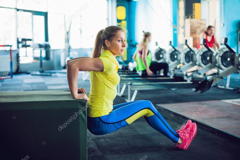 Girl in fitness club. young sportswoman doing squats using bench in gym