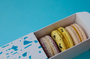 Çok güzel macarons. En baştan görüntüleyin. Mavi bir arka plan üzerinde bir kutuya