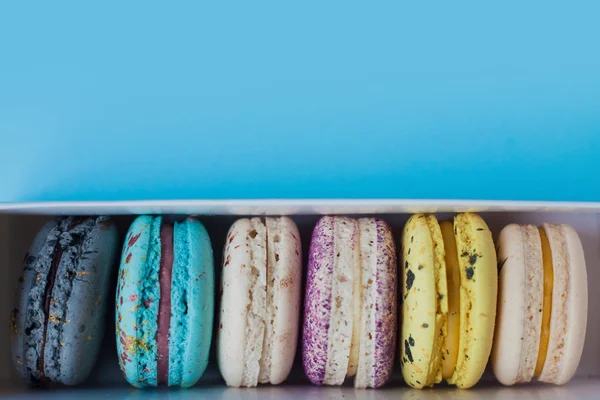 Çok güzel macarons. En baştan görüntüleyin. Mavi bir arka plan üzerinde bir kutuya