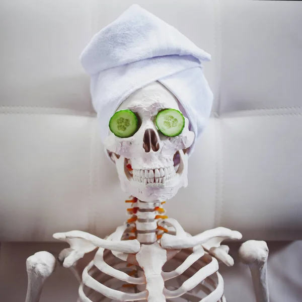 Σκελετός σε Κομμωτήριο Spa με πετσέτα στο κεφάλι και μάσκα στο πρόσωπό της, χαλαρώνει, περίθαλψη οι ίδιοι. Μια παράλογη ιδέα, κοινωνική παρωδία. Αναλάβει τη φροντίδα της ομορφιάς και ξεχάστε για εσωτερική ειρήνη — Φωτογραφία Αρχείου