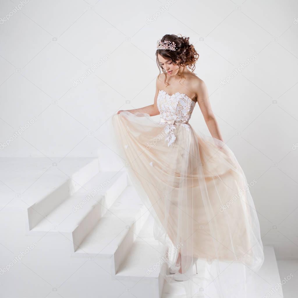 Portrait of a beautiful girl in a wedding dress. Dancing Bride, white background.