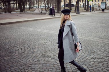 Genç, kalça ve çekici sarışın kız şık bir şapka ve gri bir ceket şehirde yürüyüş. Yaya geçidi