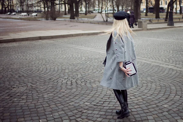 Nuori, hip ja houkutteleva blondi kävelee ympäri kaupunkia, tyttö tyylikäs hattu ja harmaa takki. Jalankulkijoiden risteys — kuvapankkivalokuva