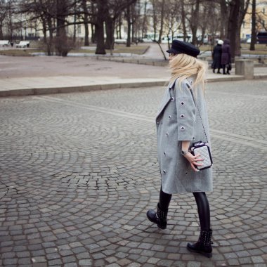 Genç, kalça ve çekici sarışın kız şık bir şapka ve gri bir ceket şehirde yürüyüş. Yaya geçidi