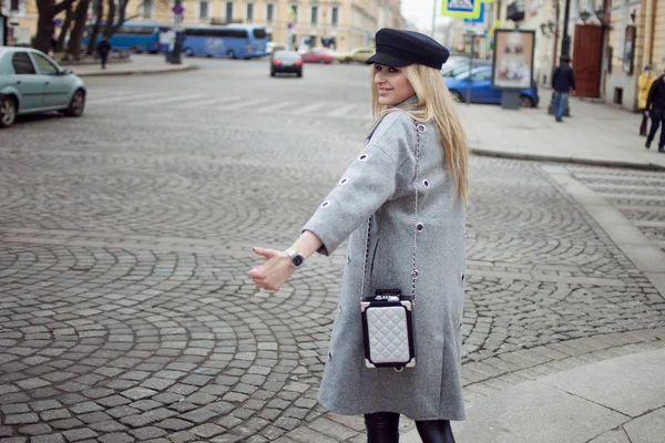 Молодая, модная и привлекательная блондинка, вызывающая такси, девушка в стильной шляпе и сером пальто — стоковое фото