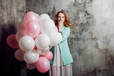 Partide balonlar büyük bir demet tutan Kızıl saçlı güzellik genç kadın beyaz bir elbise içinde.