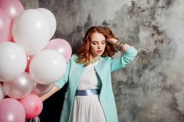 Partide balonlar büyük bir demet tutan Kızıl saçlı güzellik genç kadın beyaz bir elbise içinde.
