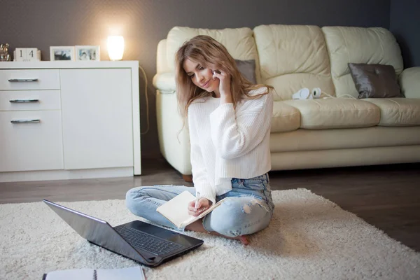 Cute blonde talking on the phone sitting on floor. Work with a laptop, freelance blogger — Stock Photo, Image
