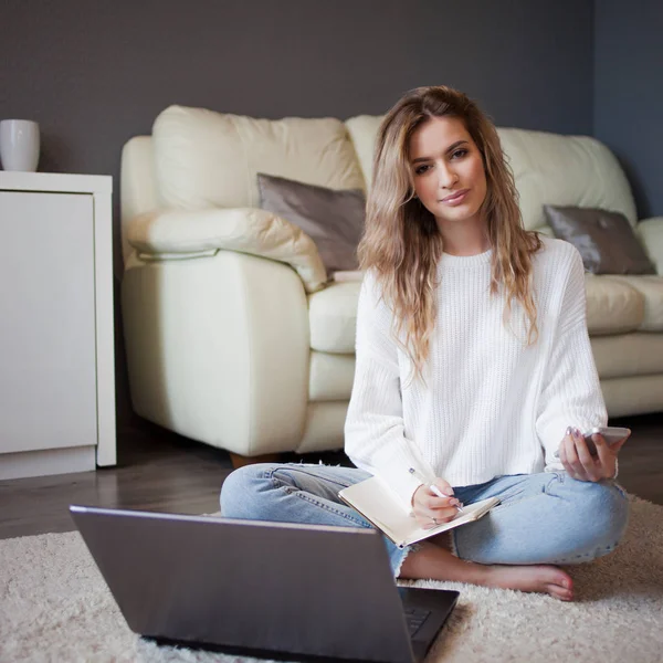 Charming young girl sitting on the floor. To work with notebook, take notes — Stock Photo, Image