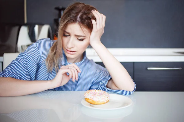 Wil eet zoete geglazuurde donut. Charmante jonge vrouw in de keuken. — Stockfoto