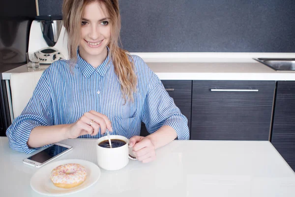 Smiling young blonde eat Breakfast at home. Coffee with donut. — Stock Photo, Image