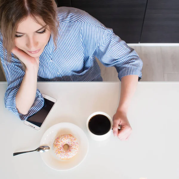 Charmante jonge blonde thuis ontbijten. Koffie met donut. Bovenaanzicht — Stockfoto