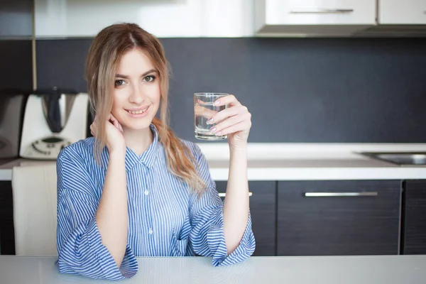 Ελκυστική νεαρή γυναίκα πόσιμου νερού στην κουζίνα. Συνήθειες για ένα υγιεινό τρόπο ζωής — Φωτογραφία Αρχείου