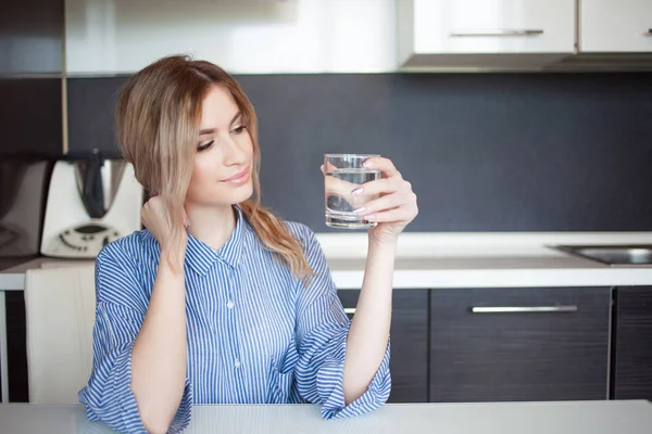 Привлекательная молодая женщина пьет воду на кухне. Привычки к здоровому образу жизни — стоковое фото