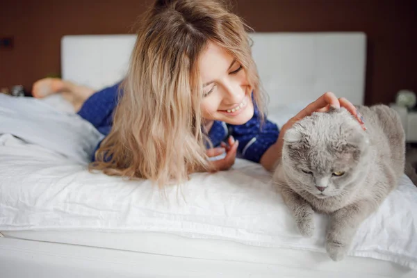 Portréja egy gyönyörű nő, a pizsama otthon, az ágyban fekve. Pat a macska — Stock Fotó