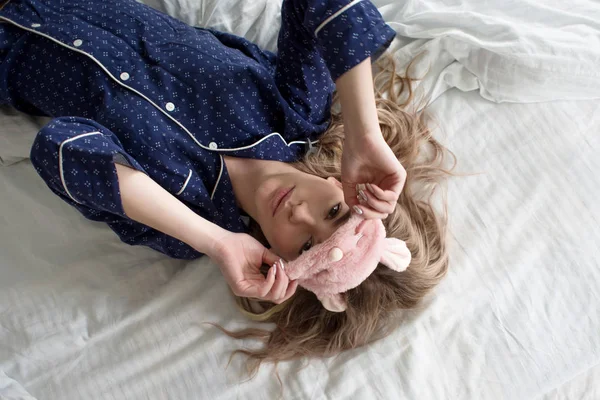 Söt blondin i sängen i blå pyjamas och sovmask, ovanifrån — Stockfoto