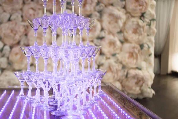 Pirâmide de copos de champanhe em festa de casamento. Fundo floral — Fotografia de Stock