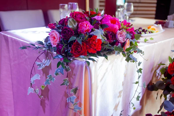 Bryllupsindretning. Røde Blomster i restauranten, borddækning - Stock-foto