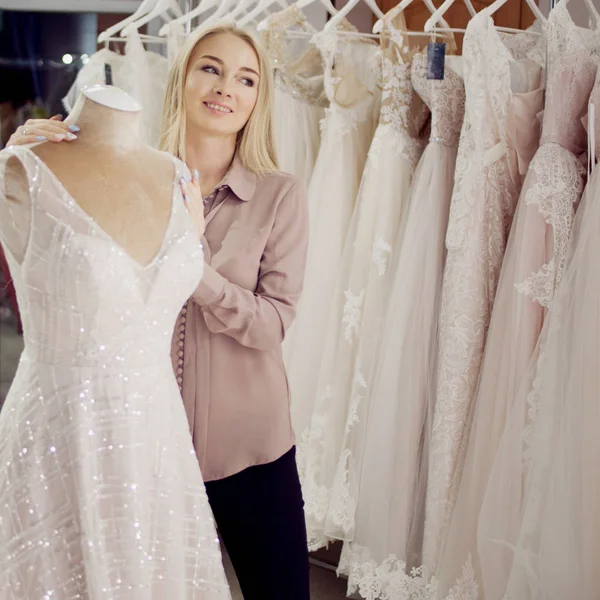 Belle jeune femme dans un salon de mariée, choisissez robe sur le mannequin — Photo