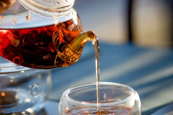 Tee in einer Teekanne, gießen Sie Tee in Glas Tasse. Glas Teekanne, Tasse, Nahaufnahme — Stockfoto