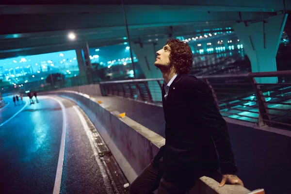 Fiatal stílusos srác a háttérben az éjszakai város, város fényei — Stock Fotó