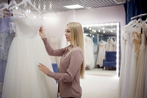 Schöne Mädchen wählt ihr Hochzeitskleid. Jungunternehmerin. Porträt im Brautsalon — Stockfoto