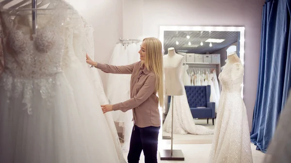 Piękna dziewczyna wybiera suknię ślubną. Młoda kobieta przedsiębiorcy. Portret w Bridal salon — Zdjęcie stockowe