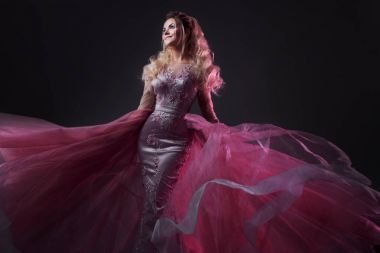 Bir tren şık pembe elbiseli çekici bayan. Stüdyo portre gri arka plan üzerinde