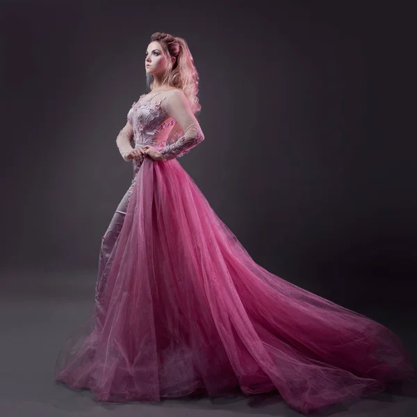 Glamorosa dama en un elegante vestido rosa con un tren. Retrato de estudio sobre fondo gris — Foto de Stock