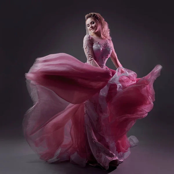 Glamorosa dama en un elegante vestido rosa con un tren. Retrato de estudio sobre fondo gris — Foto de Stock