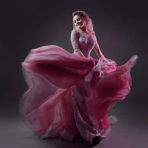 Glamorous lady in a chic pink dress with a train. Studio portrait on gray background — Stock Photo, Image